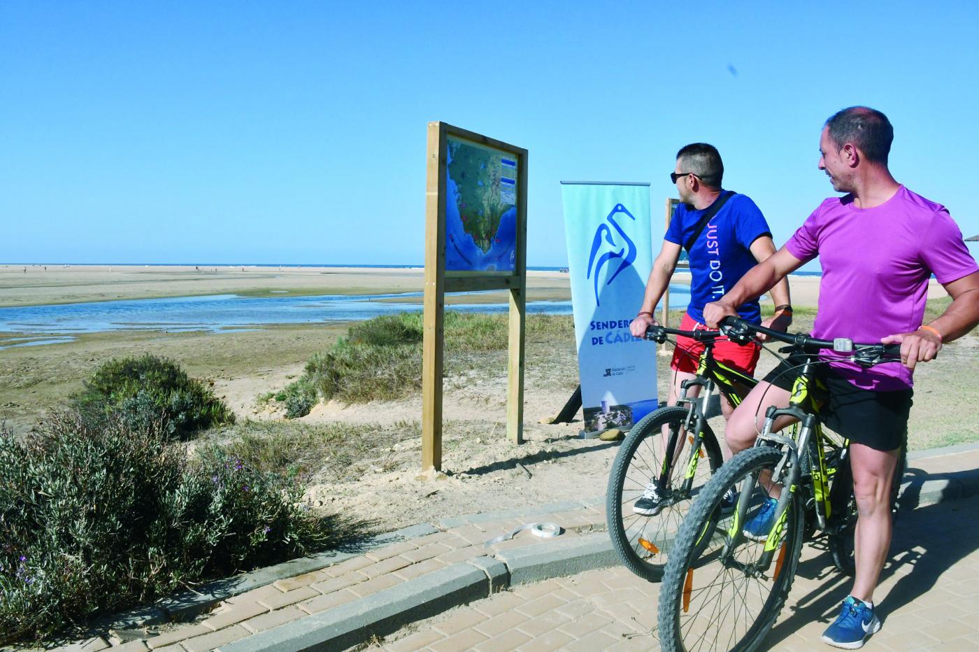 Ciclistas mirando el mapa de Senderos de Cádiz.  Diputación