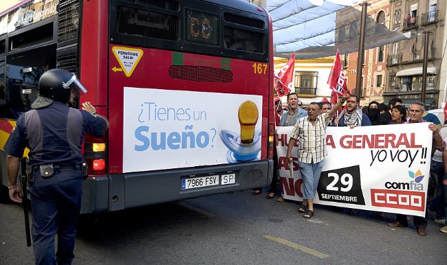 Un policía ayuda a maniobrar a un autobús de servicios mínimos. EFE
